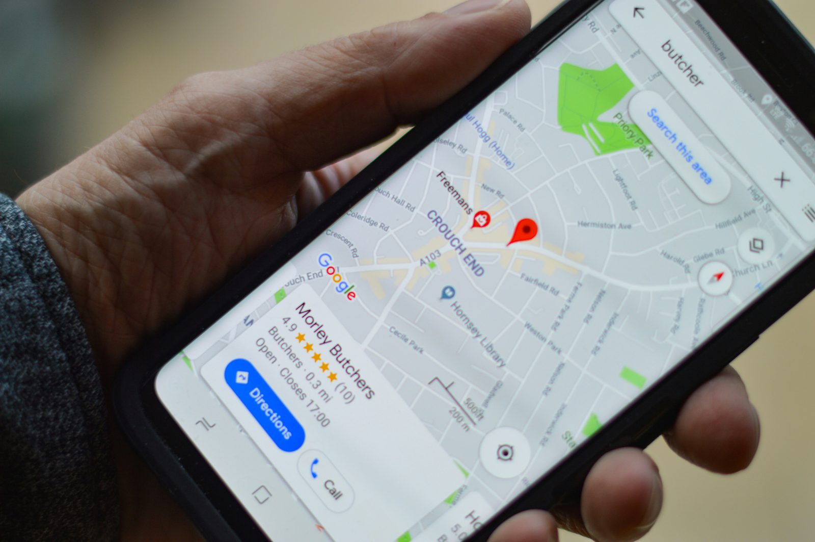 Hand holding a smartphone showing Google Maps with local business pins